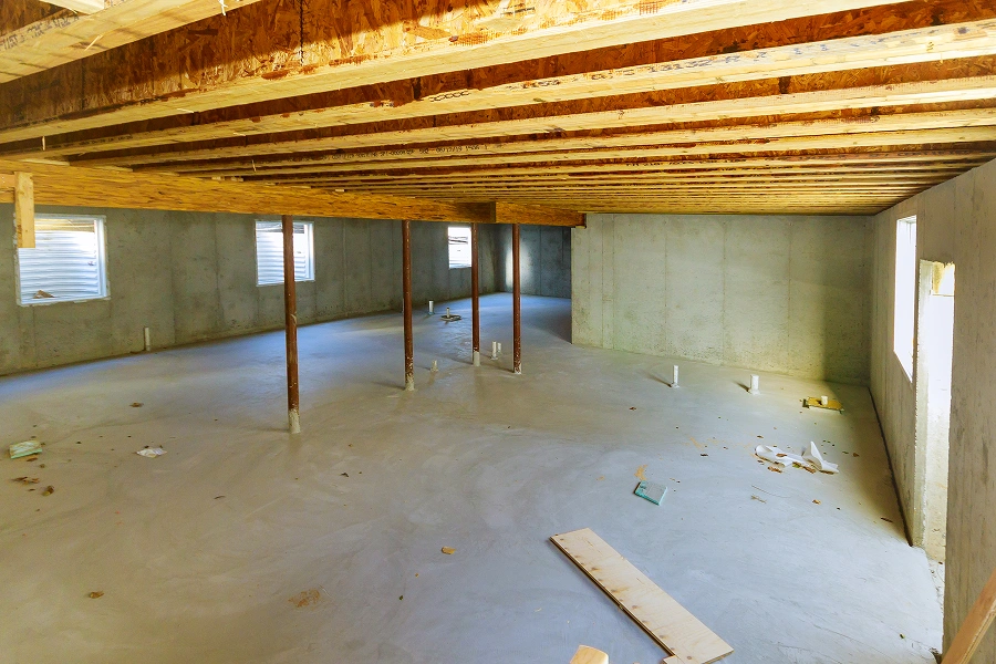 Unfinished basement with concrete floor and beams.