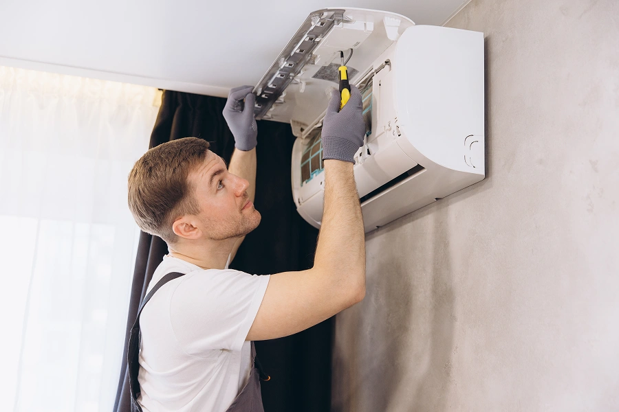 Technician repairing wall-mounted air conditioner.