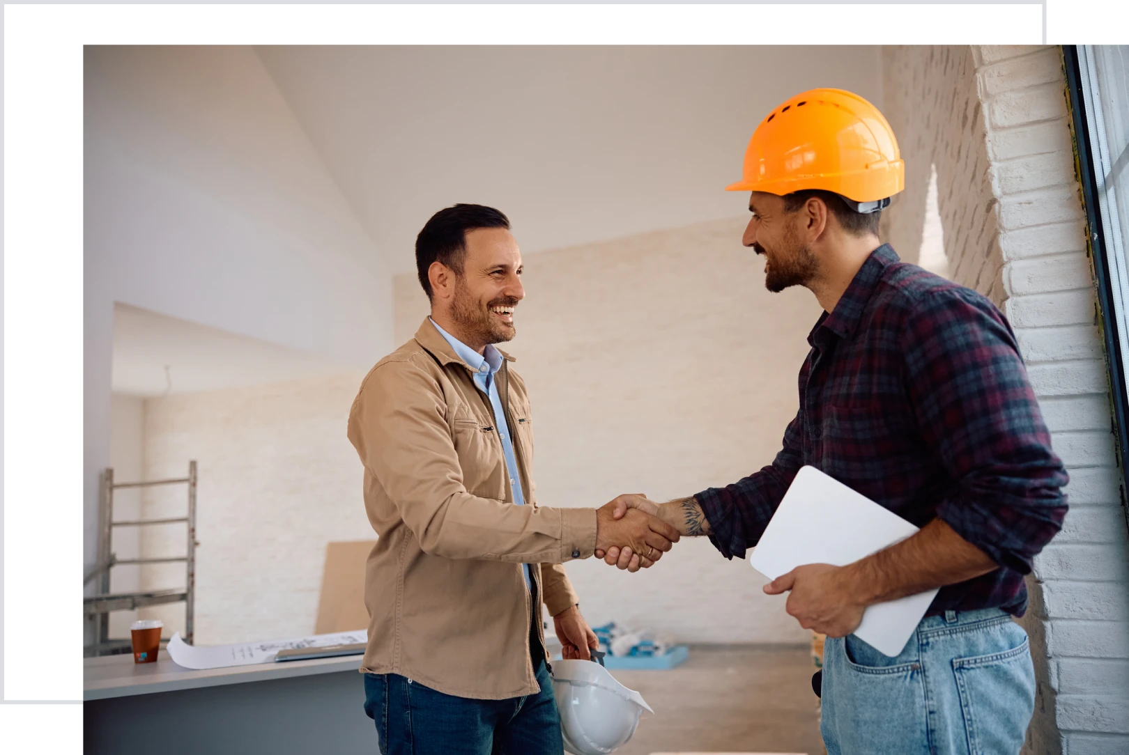 Two men shaking hands in construction setting.