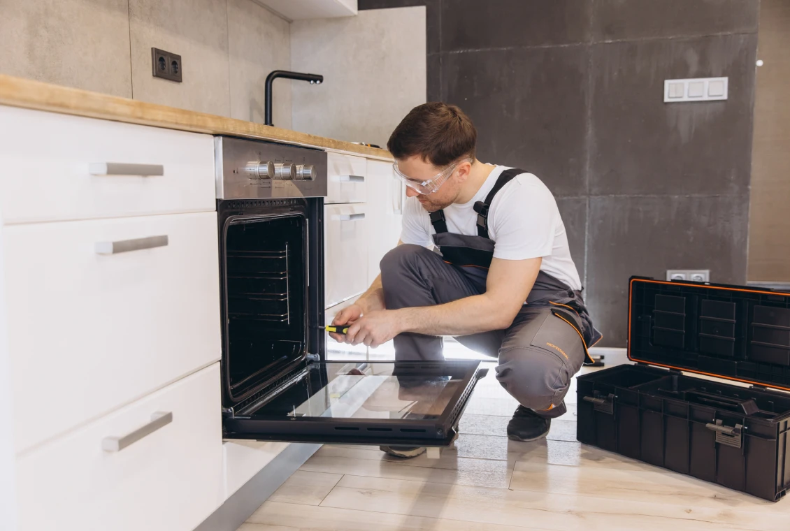 Technician repairing oven in modern kitchen.