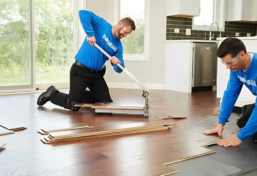 Men installing hardwood flooring in a room.