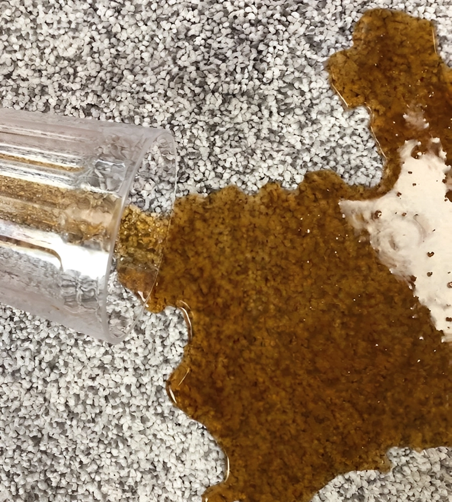 Spilled coffee on carpet from glass cup.